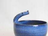 a blue bowl with a handle on a white surface