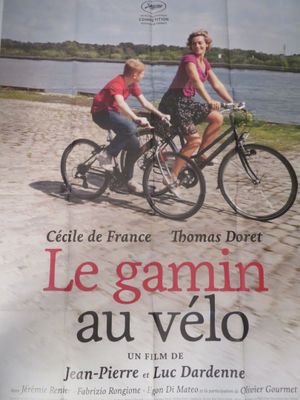 une affiche représentant un couple faisant du vélo sur la plage