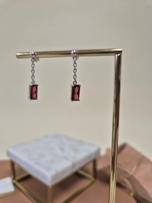 a pair of earrings that are sitting on a stand