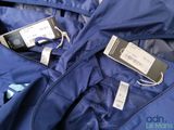a blue jacket with tags on it and a cell phone in the pocket