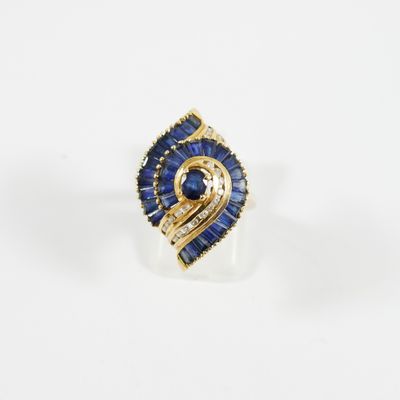 gros plan d'une bague en or avec saphirs bleus et diamants