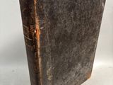 an old book sitting on top of a white table next to a clock