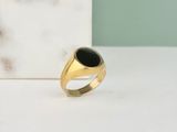 gros plan d'une bague en or contenant une pierre noire