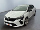 La voiture blanche est garée dans une grande pièce au sol gris.