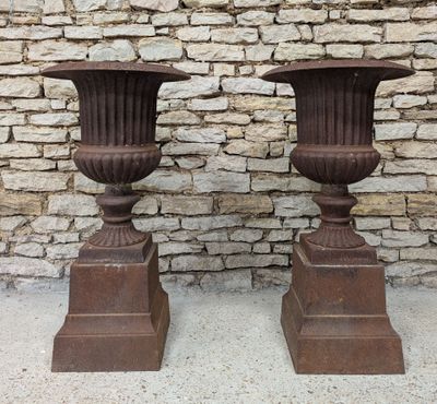deux grands vases placés l'un à côté de l'autre devant un mur de briques