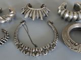 des bijoux en argent posés sur une table, avec un bracelet en argent et d’autres objets