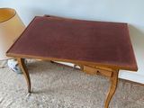 a small table with a brown leather top next to a lamp