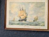 un tableau représentant un bateau accroché au mur, à côté de deux photos encadrées