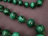 a close up of a necklace with green beads on a table