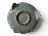 a green vase with a hole in it on a white surface