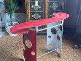 a red surfboard on a metal stand in a living room