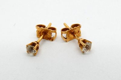 a pair of gold earrings with diamonds on a white surface
