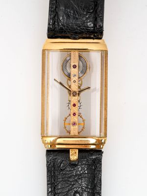 une montre en or avec un bracelet en cuir noir posée sur un fond blanc