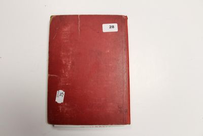 un vieux livre rouge posé sur une table blanche