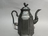 une théière en argent ornée d'un oiseau