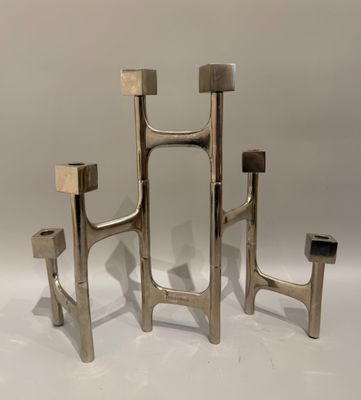 trois bougies en métal posées sur une surface blanche