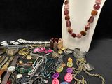 many different necklaces and bracelets on a table