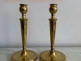 pair of brass candlesticks on a marble table with a pink shade