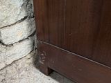 a wooden cabinet sitting on the floor next to a stone wall
