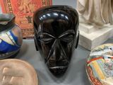 a black mask sitting on top of a table next to other vases