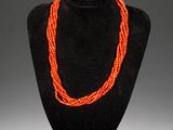 an orange beaded necklace on a black mannequin