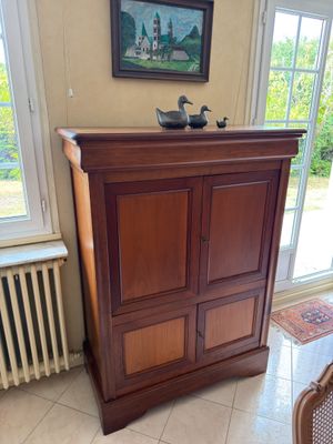a cabinet in the corner of a room with a painting on the wall