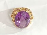 a close up of a purple stone ring on a white surface