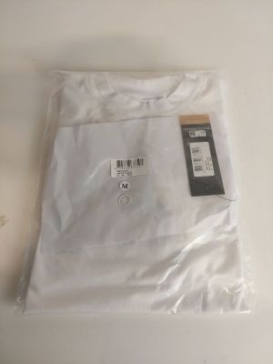 une chemise blanche posée sur une table blanche, avec une étiquette dessus
