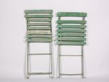 two green chairs sitting next to each other on a white surface
