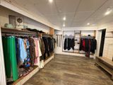 une photo d'un magasin de vêtements où les portants sont remplis de vêtements