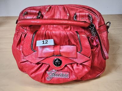 someone is holding a red purse with a name tag on it