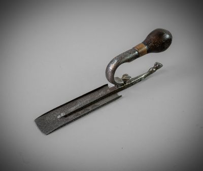 a metal object with a wooden handle on a white surface