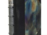 an old book with a black cover and a blue and purple cover