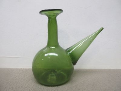 un vase en verre vert avec un couvercle noir posé par terre
