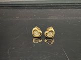 two gold earrings with diamonds on them sitting on a black surface