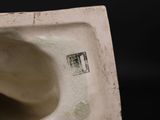 a white vase with a hole in it on a black background