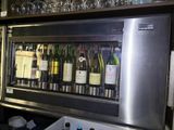 bottles of wine are lined up in a wine cooler in a bar