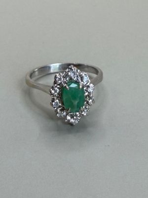 a picture of a ring with a green stone surrounded by white diamonds