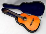 une guitare acoustique dans son étui, posée sur une surface blanche