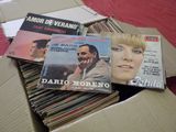 a lot of records in a cardboard box on a bed