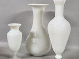 three white vases sitting next to each other on a table