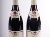 two bottles of red wine sitting next to each other on a white surface