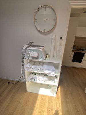 une photo d'une pièce avec une horloge accrochée au mur et des vêtements posés sur une étagère