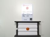 une pierre orange posée sur une étagère, à côté d'un porte-cartes de visite