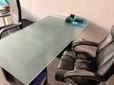 a glass desk with a chair and a computer on it