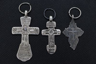 three silver crosses are displayed on a black surface