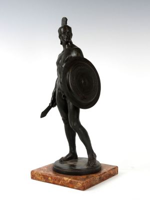 une statue en bronze représentant un homme tenant un bouclier et un bouclier
