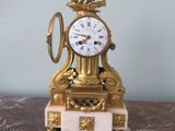 a gold clock sitting on top of a marble table