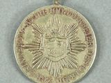 an image of a gold medal with a sunburst on it