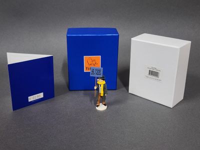 une petite figurine représentant un homme debout à côté d'une boîte